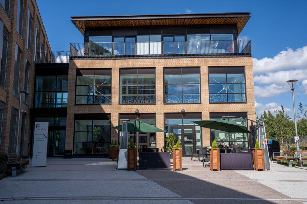 Exterior view of the plaza with outdoor seating for the cafe and the entrance leading to reception